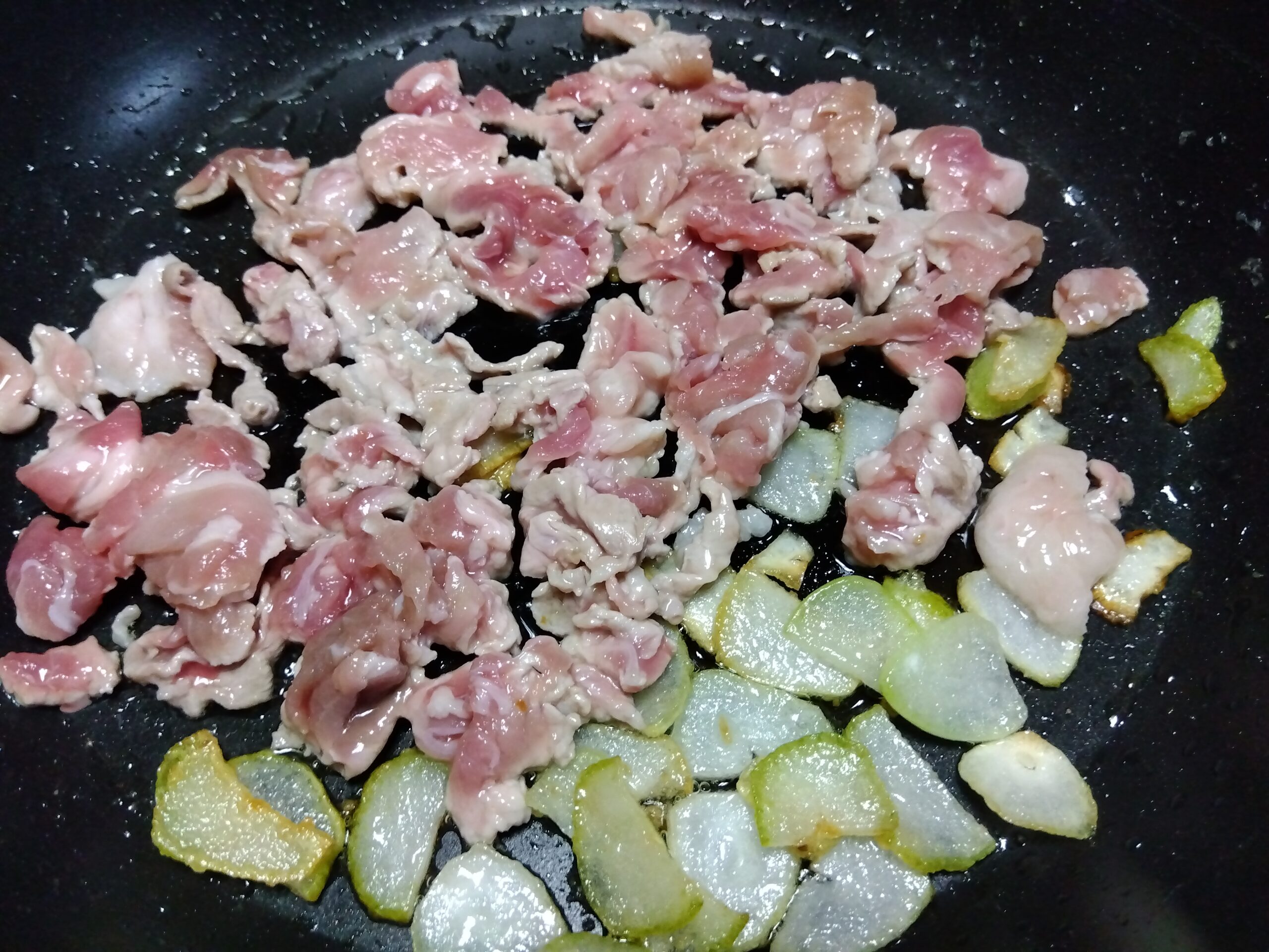 豚肉とニンニクを炒めている