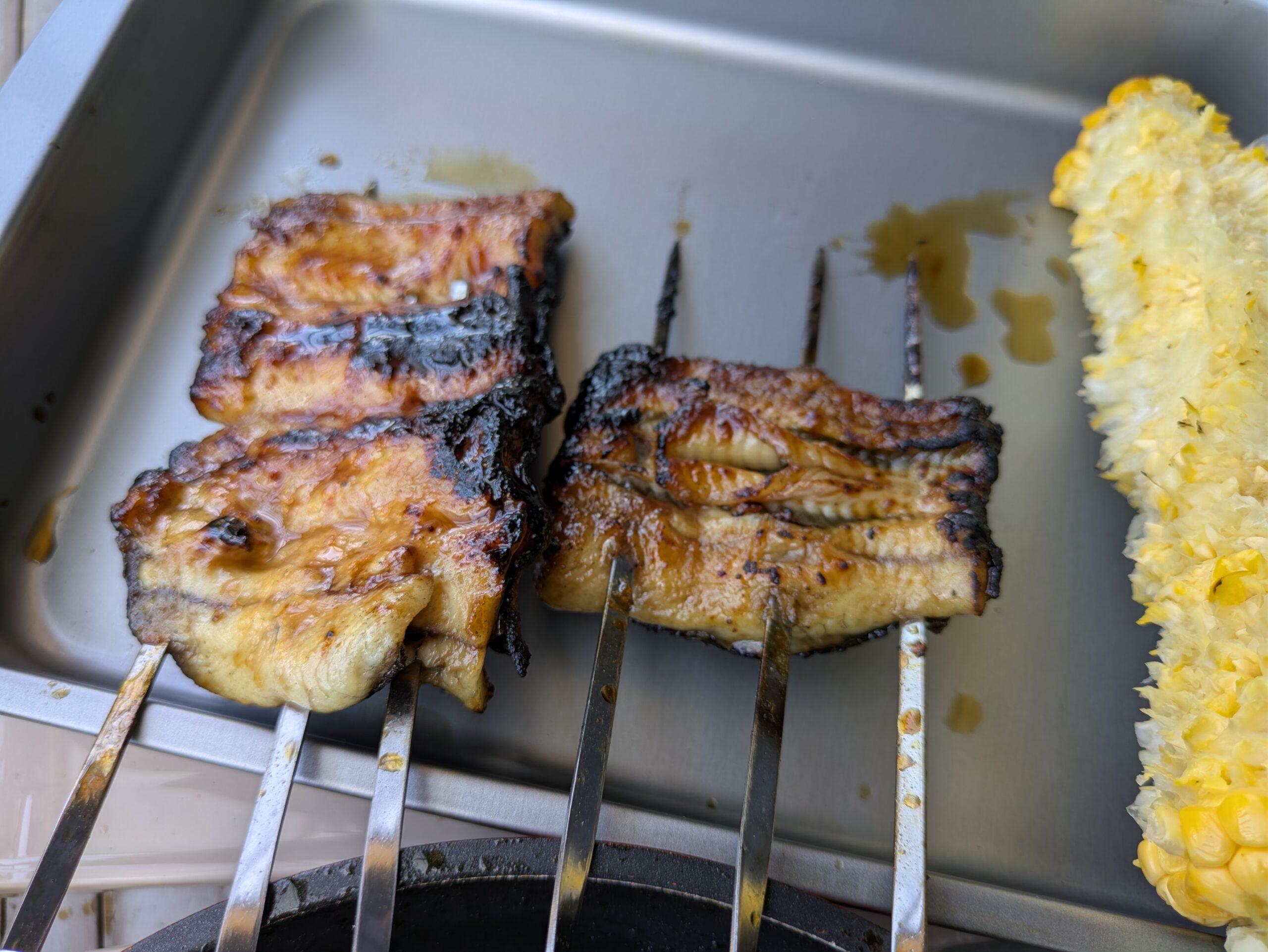 焼きあがったウナギのかば焼きと食べ終わったトウモロコシ