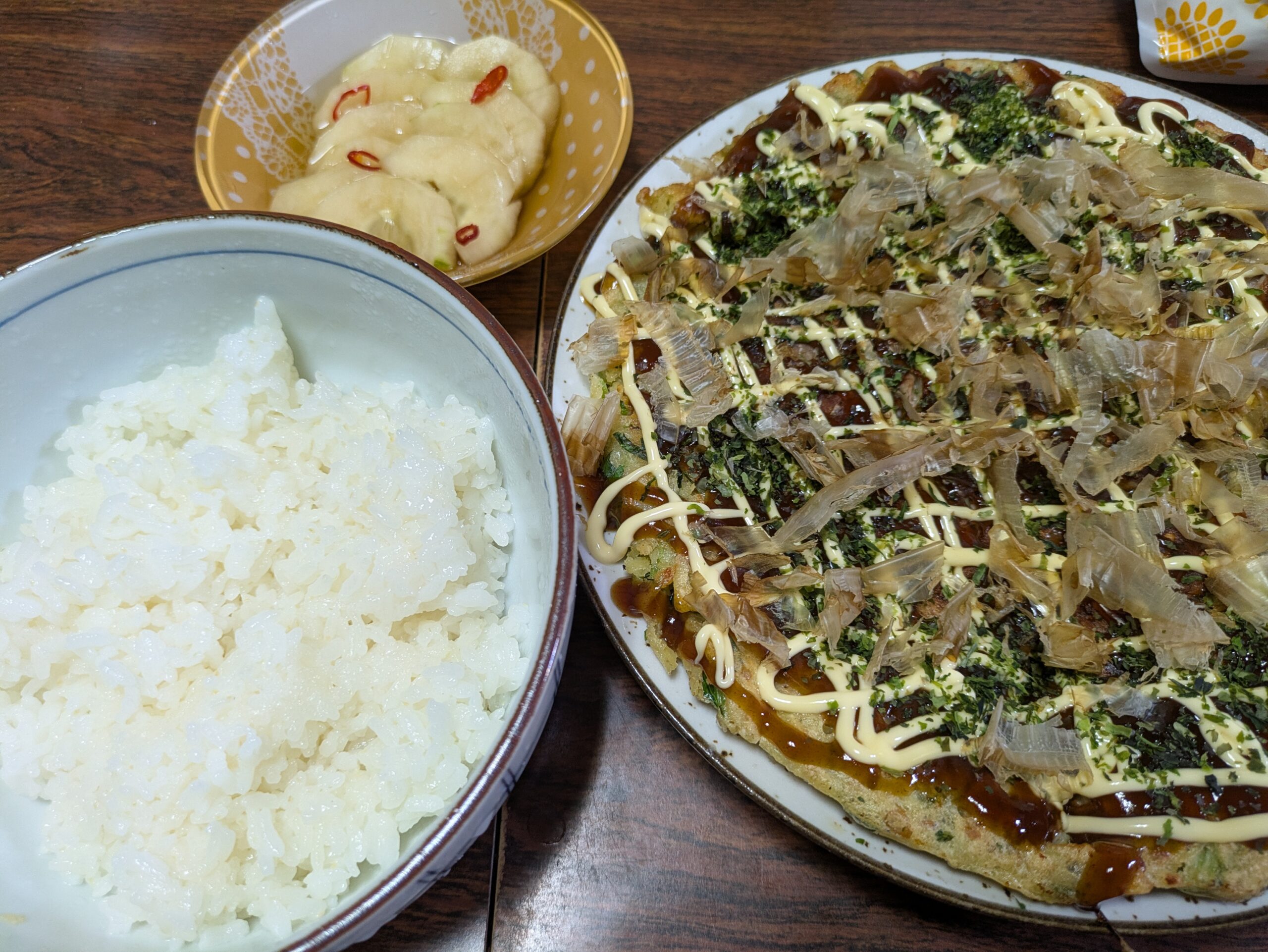 納豆と小松菜と豚肉のお好み焼きに白ご飯と加賀太胡瓜の漬物がついている