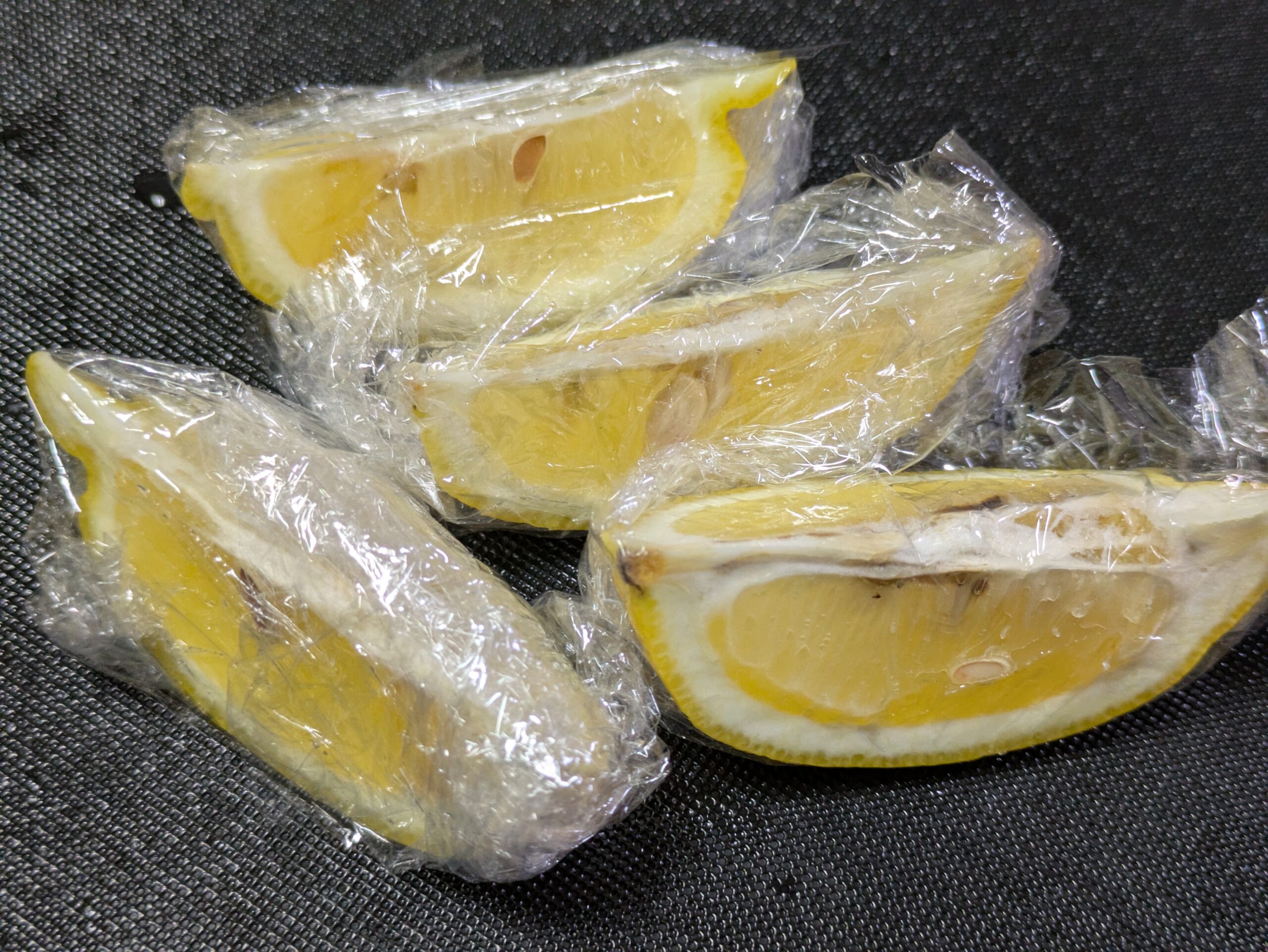 くし切りにしたレモンを冷凍保存用にラップに包んでいる