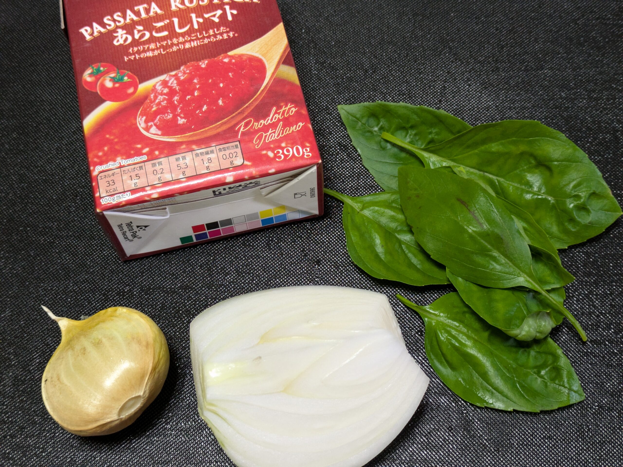 トマトソースの材料のトマトピューレ、バジル、ニンニク1片、タマネギ4分の1個