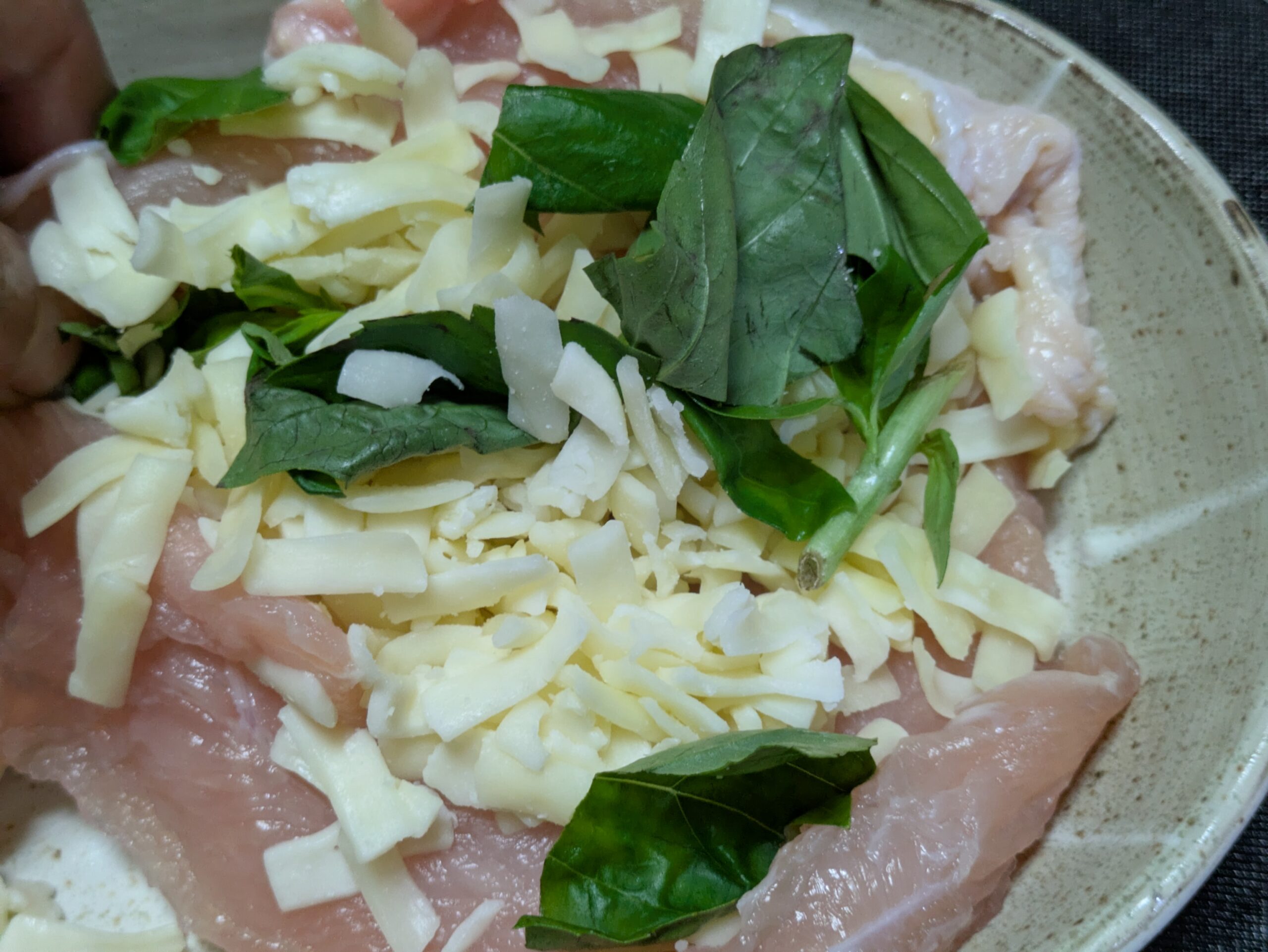 開いた鶏むね肉にチーズとバジルを乗せている
