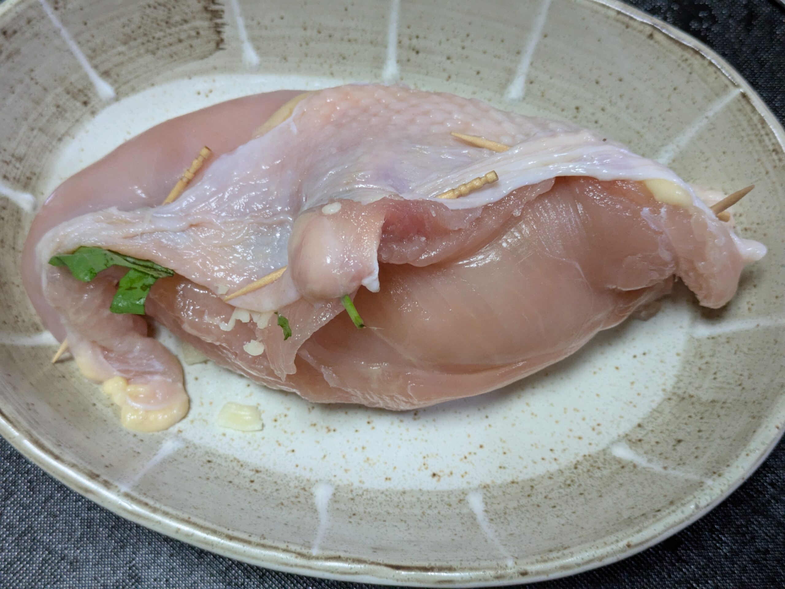 鶏むね肉でチーズとバジルを包んでいる。爪楊枝でフタをしてある