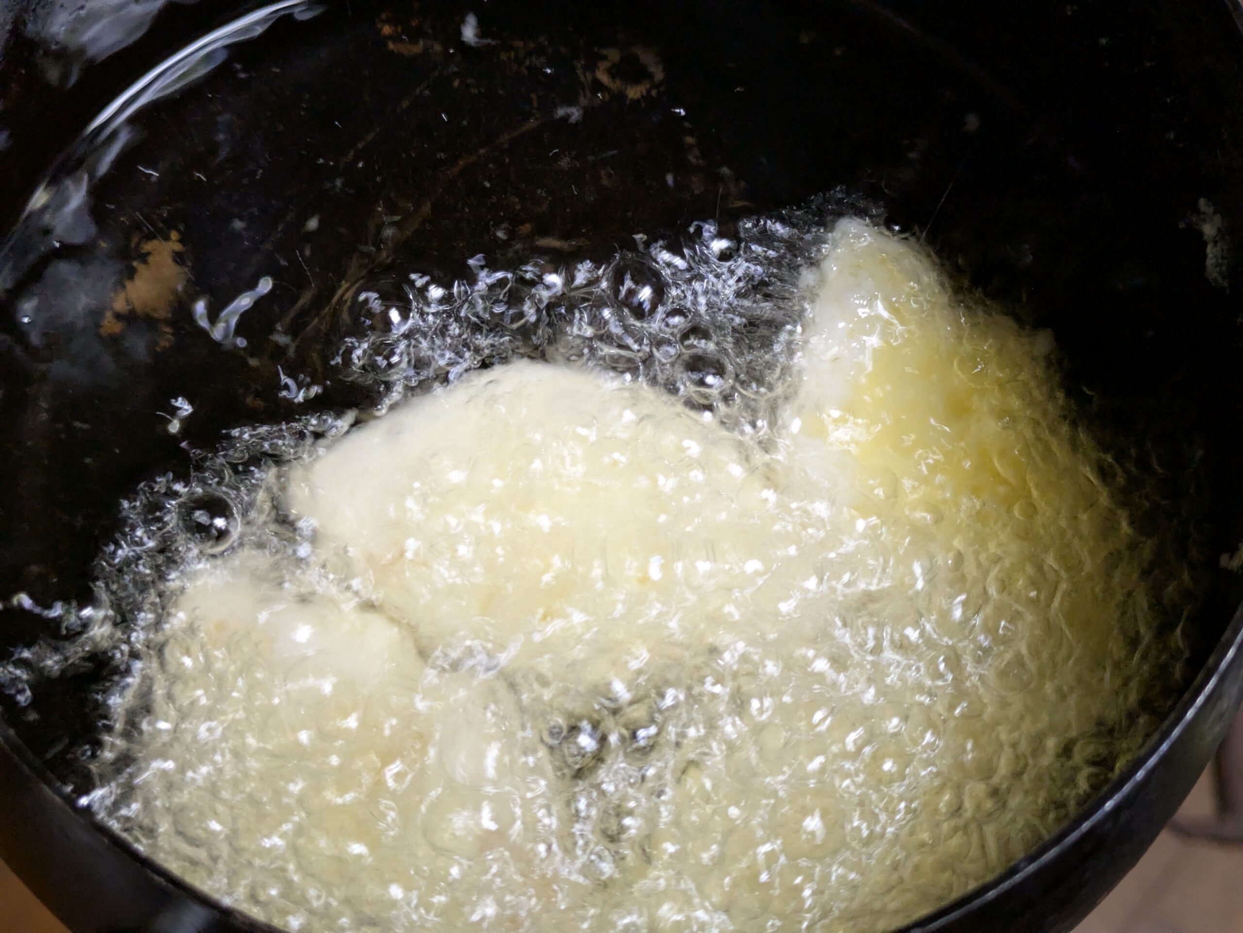 片栗粉をまぶしたパイナップルを油で揚げている様子
