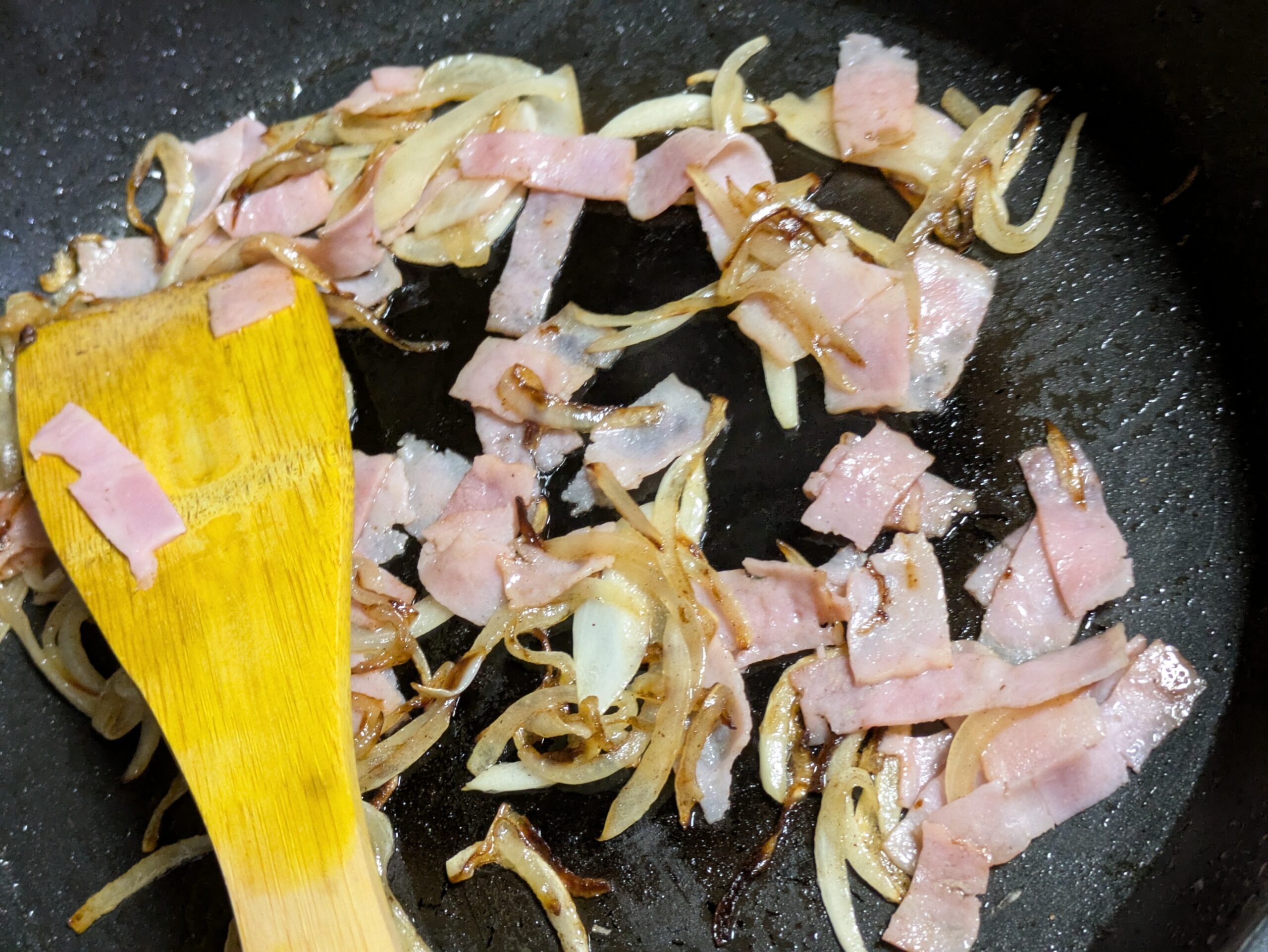 フライパンで玉ねぎとベーコンを炒めている様子