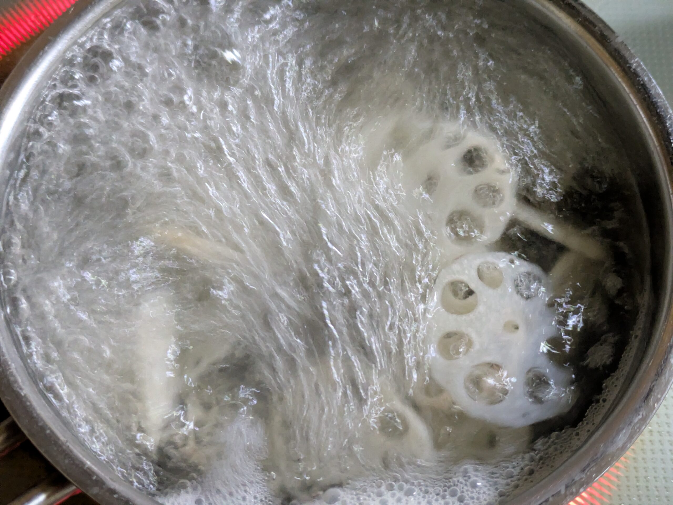 酢を加えた熱湯で薄切りの加賀れんこんを茹でている様子