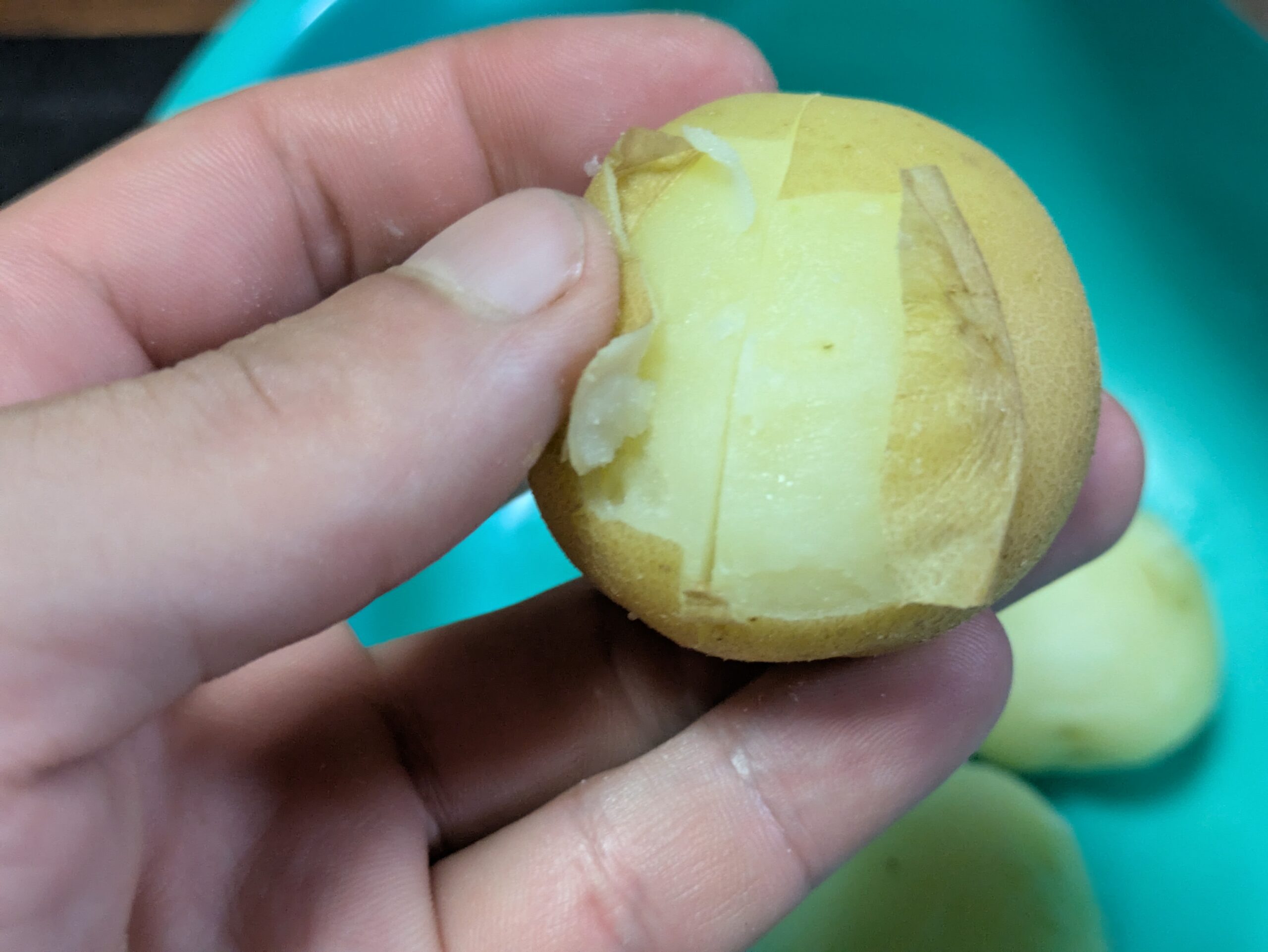 電子レンジで加熱したジャガイモの薄皮を手で剥いている様子