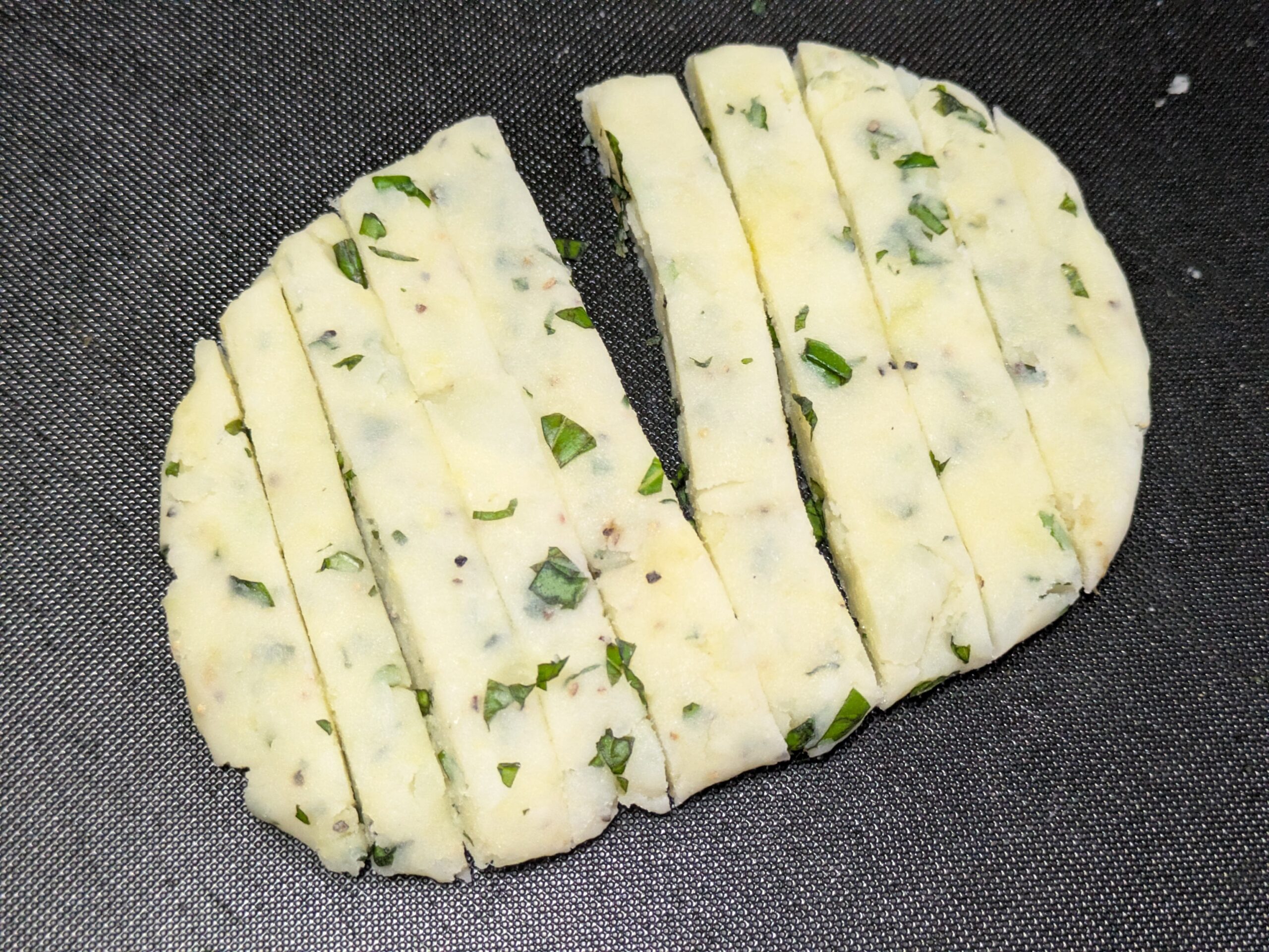 バジル入りのジャガイモ生地を細長いフライドポテトの形に整えた様子
