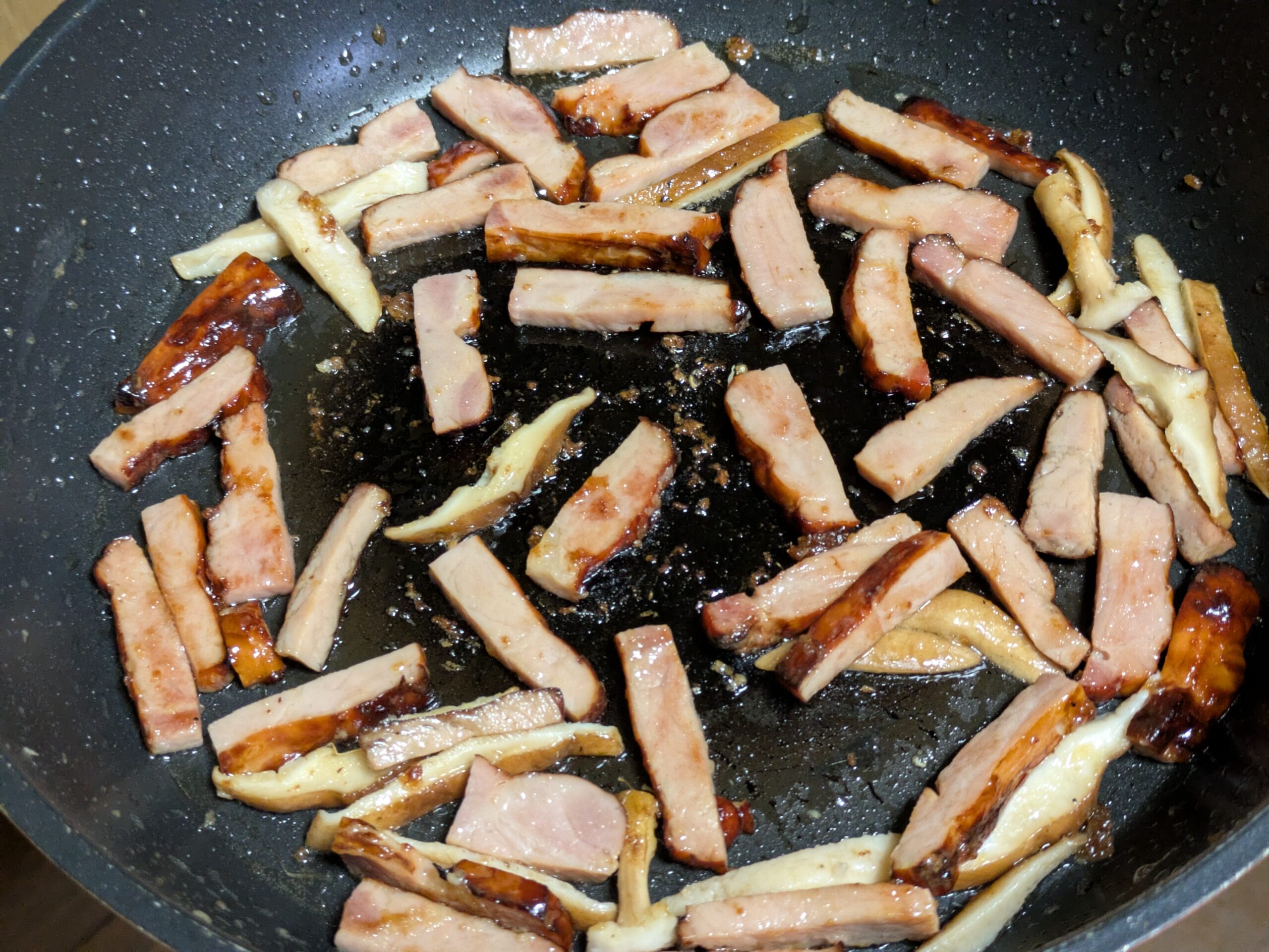 フライパンで焼き豚と椎茸を炒めている様子