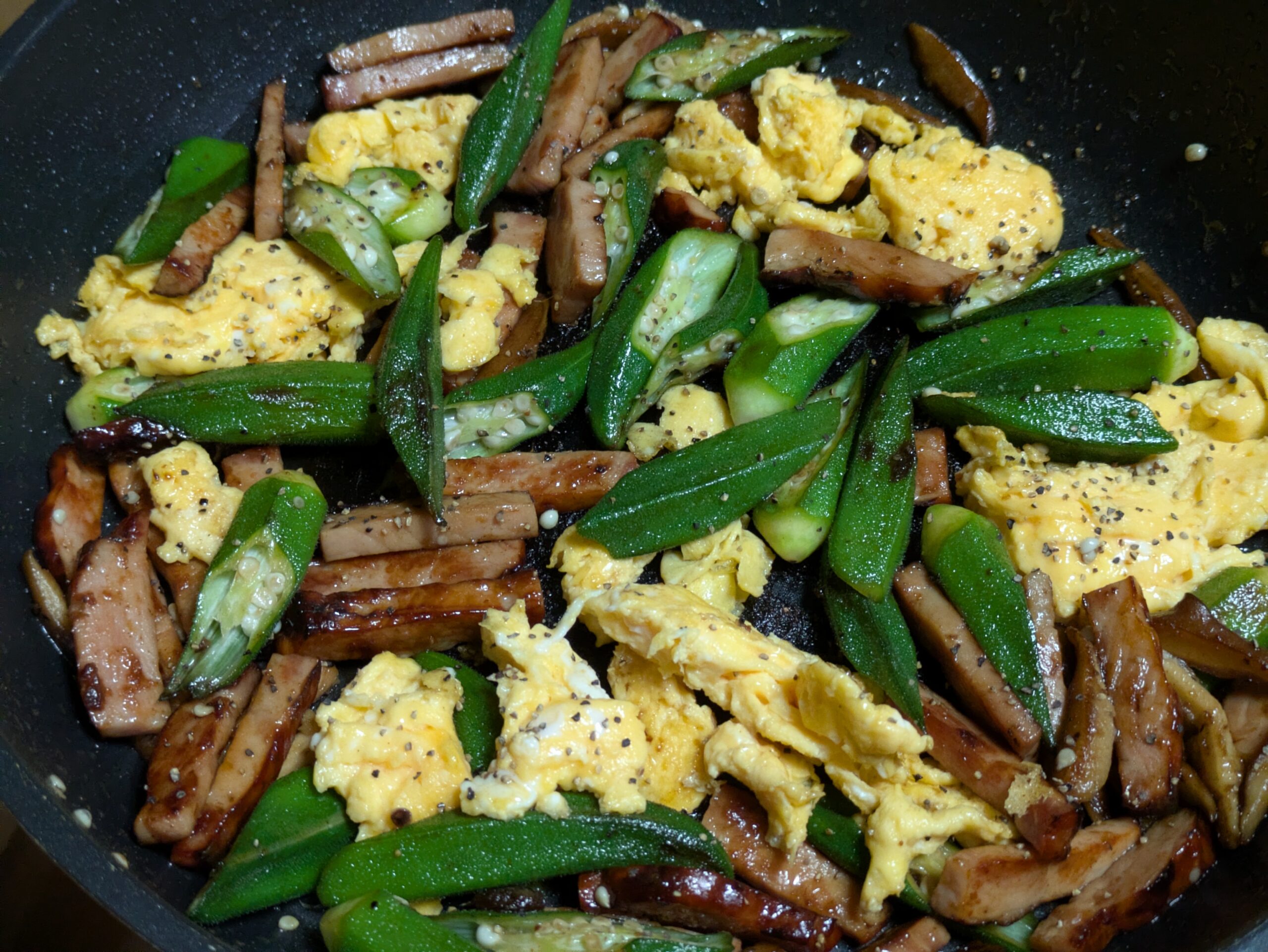 焼き豚とオクラと卵を炒め合わせている様子