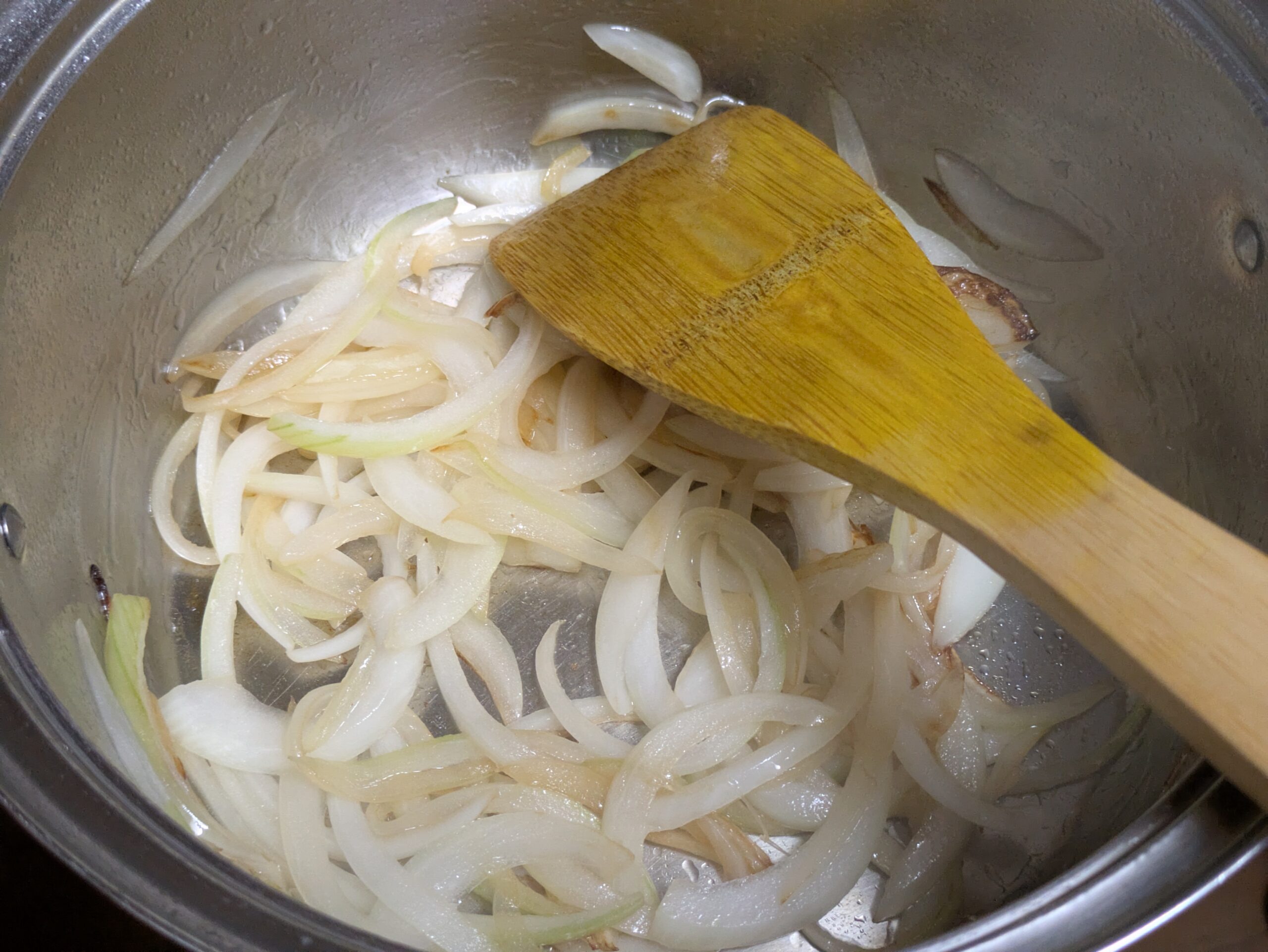 鍋に油を入れてスライスした玉ねぎを炒めている様子