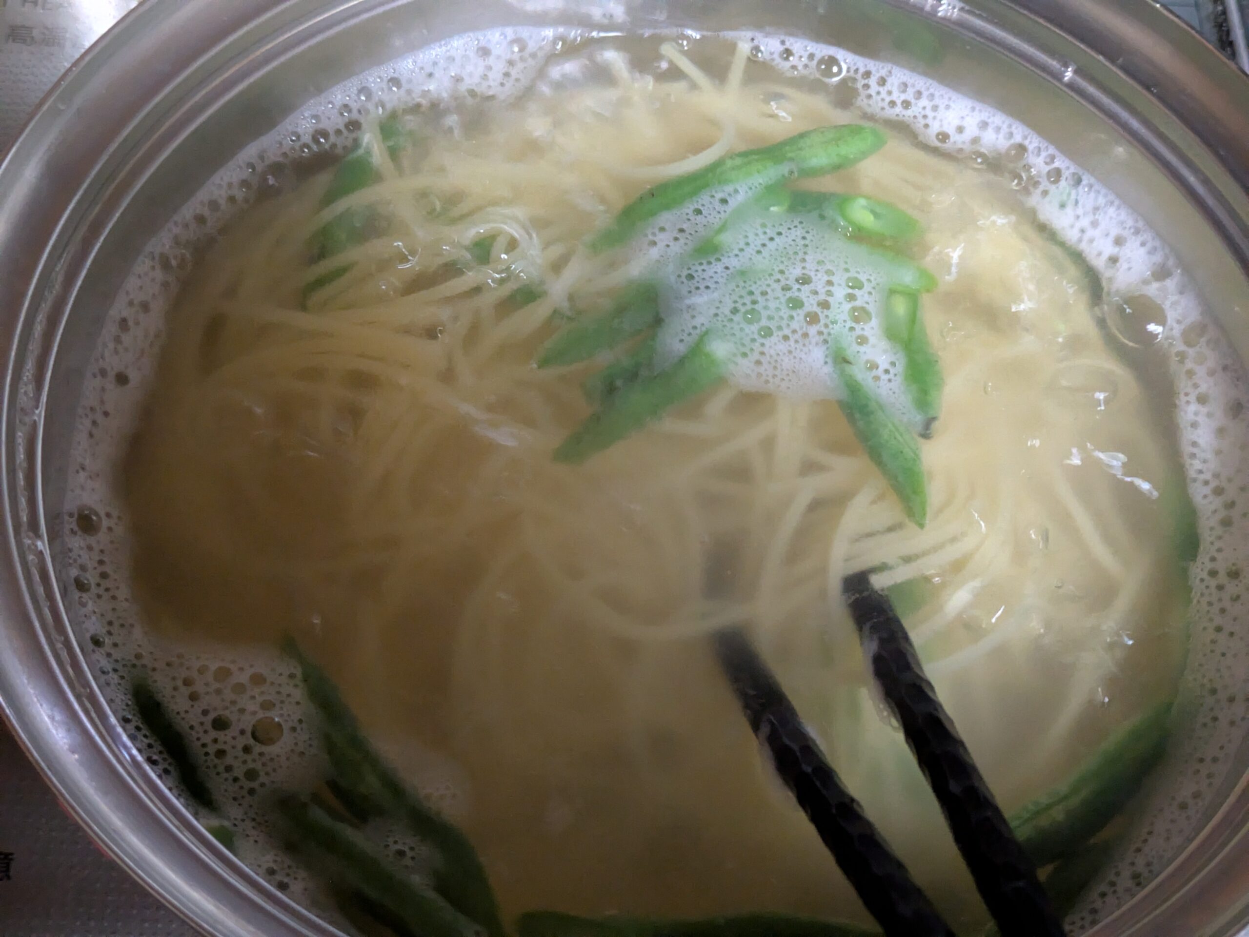 パスタの鍋につるなしインゲンを加えて一緒に茹でている様子