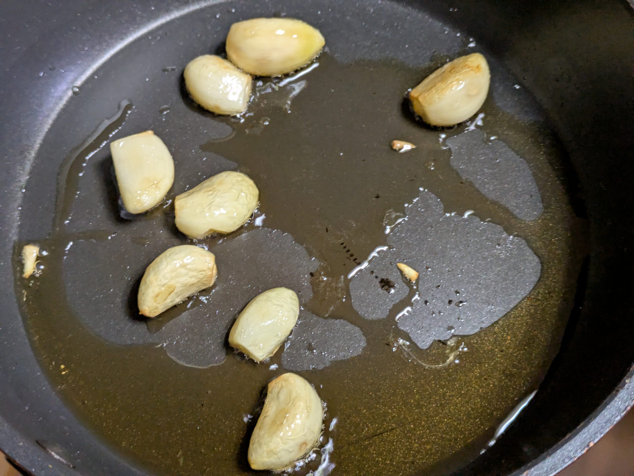 フライパンでごま油とにんにくを弱火で焼いている様子