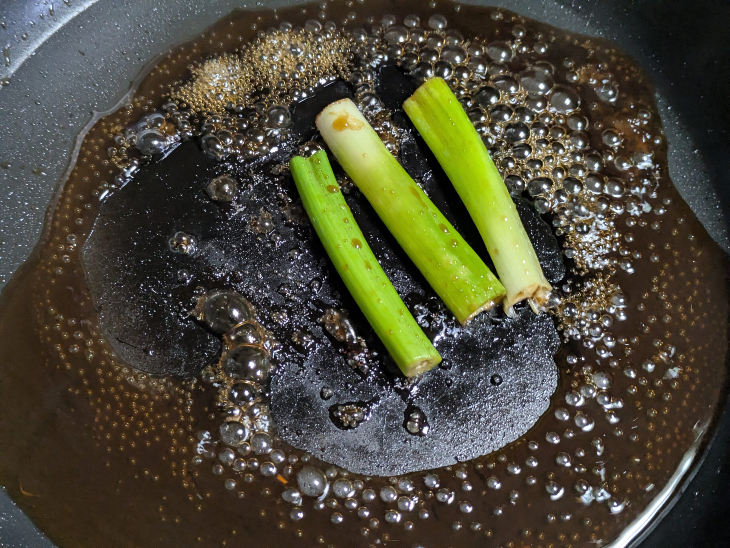 蒲焼き丼用のタレと長ネギをフライパンで煮詰めている様子