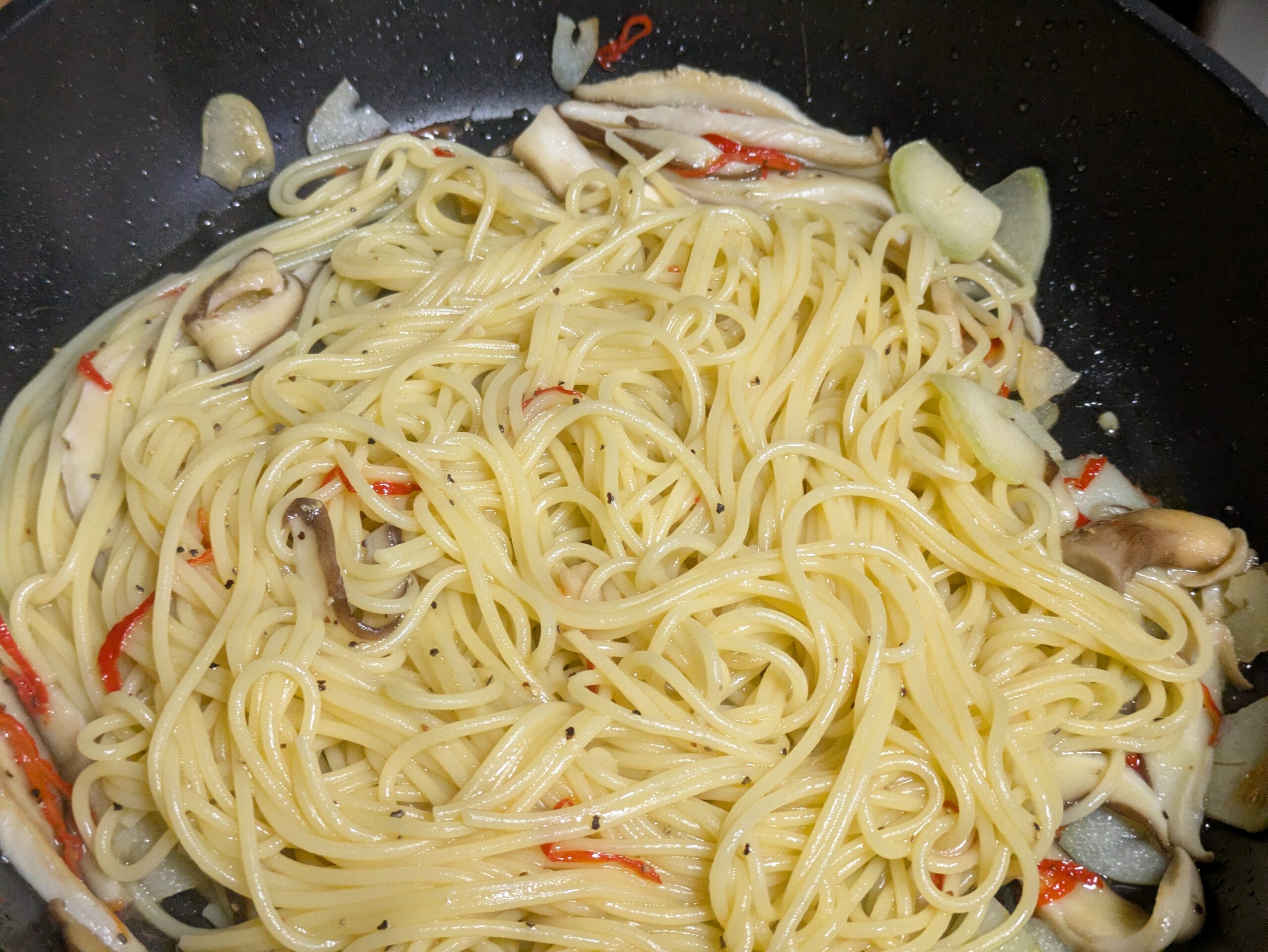 生ハバネロとニンニクと椎茸をパスタに絡めている様子