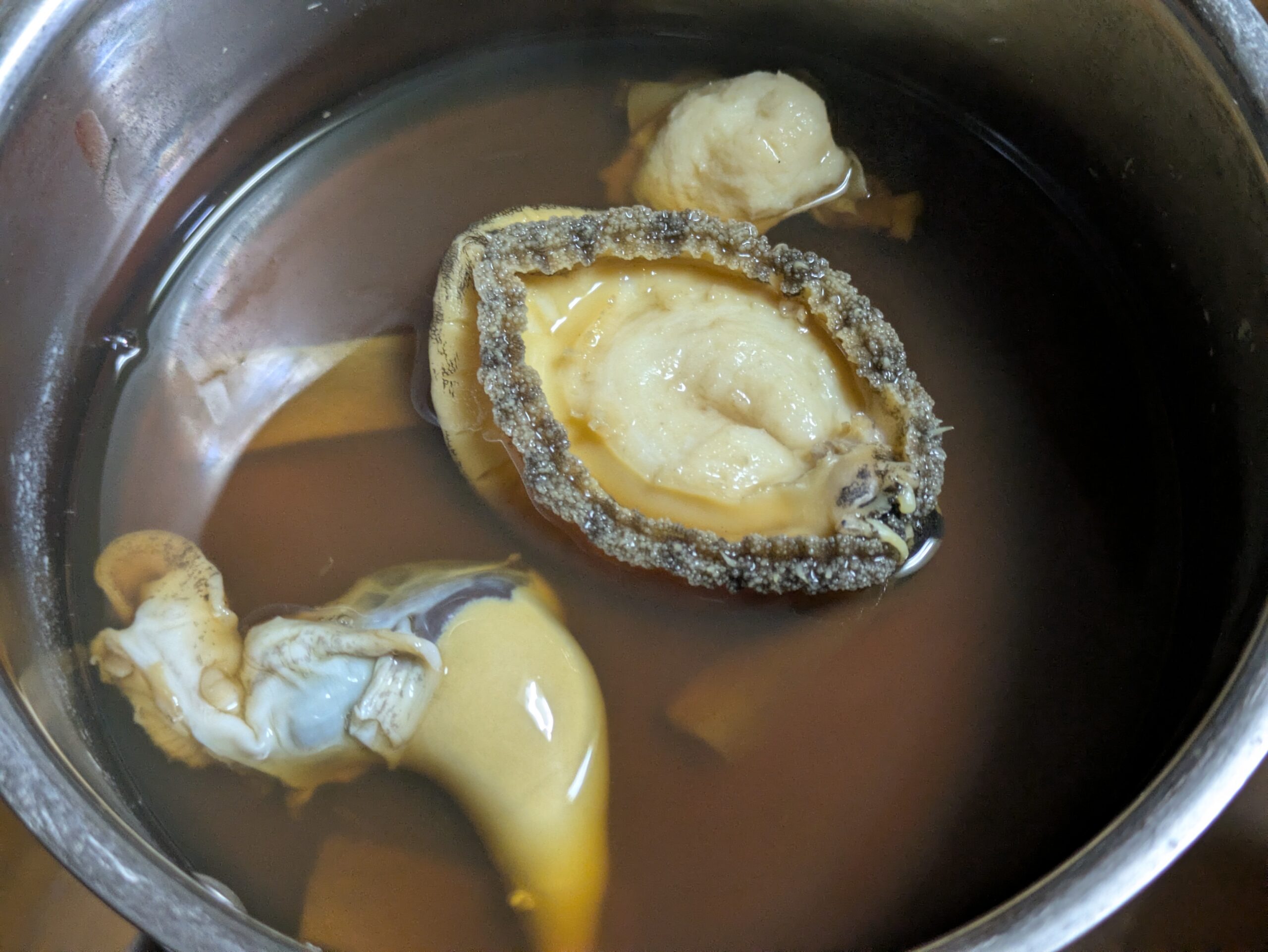 1時間煮たアワビに調味料と内臓を加える