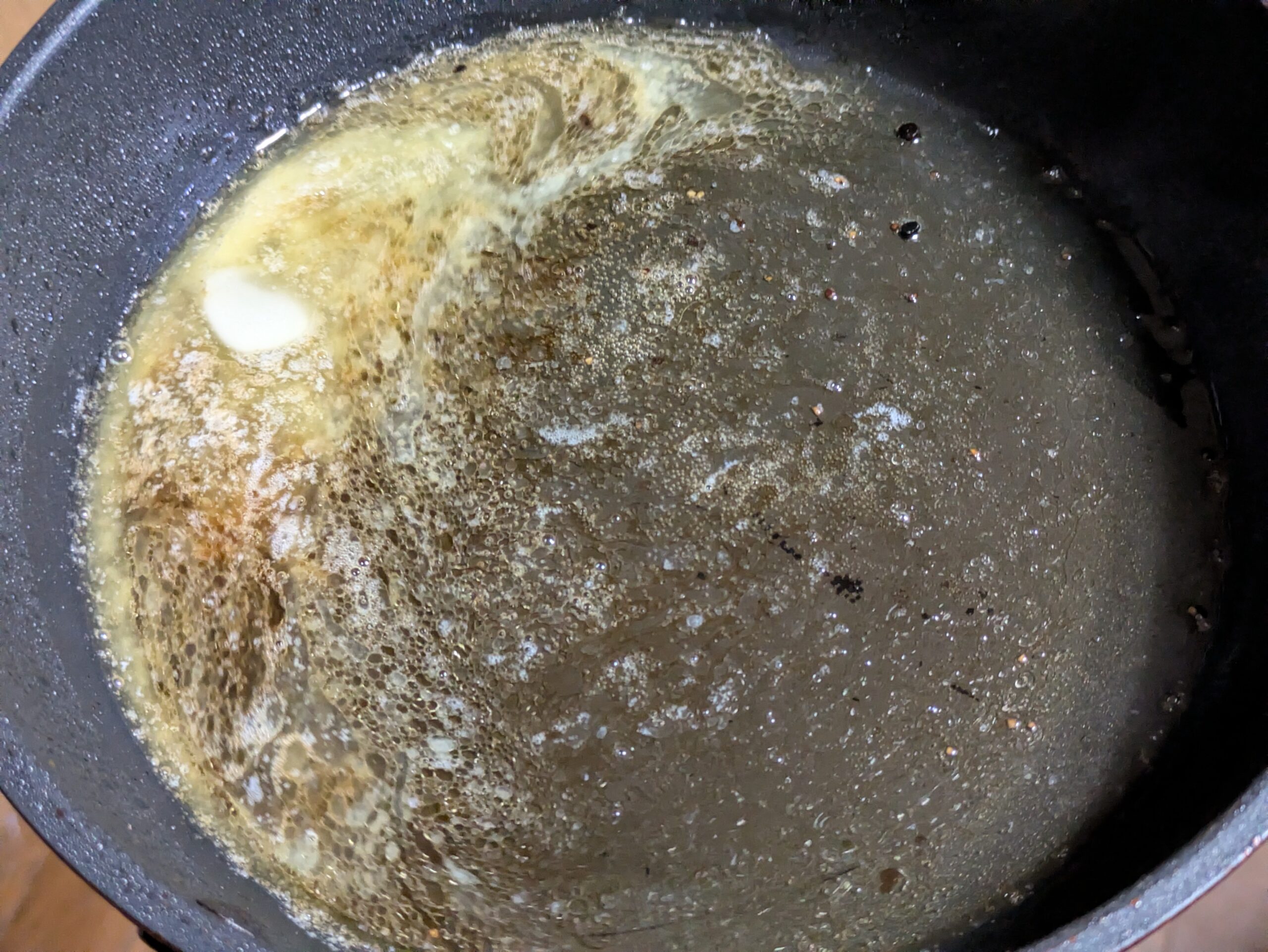 フライパンでバターと酒と醤油を加熱してソースを作っている様子