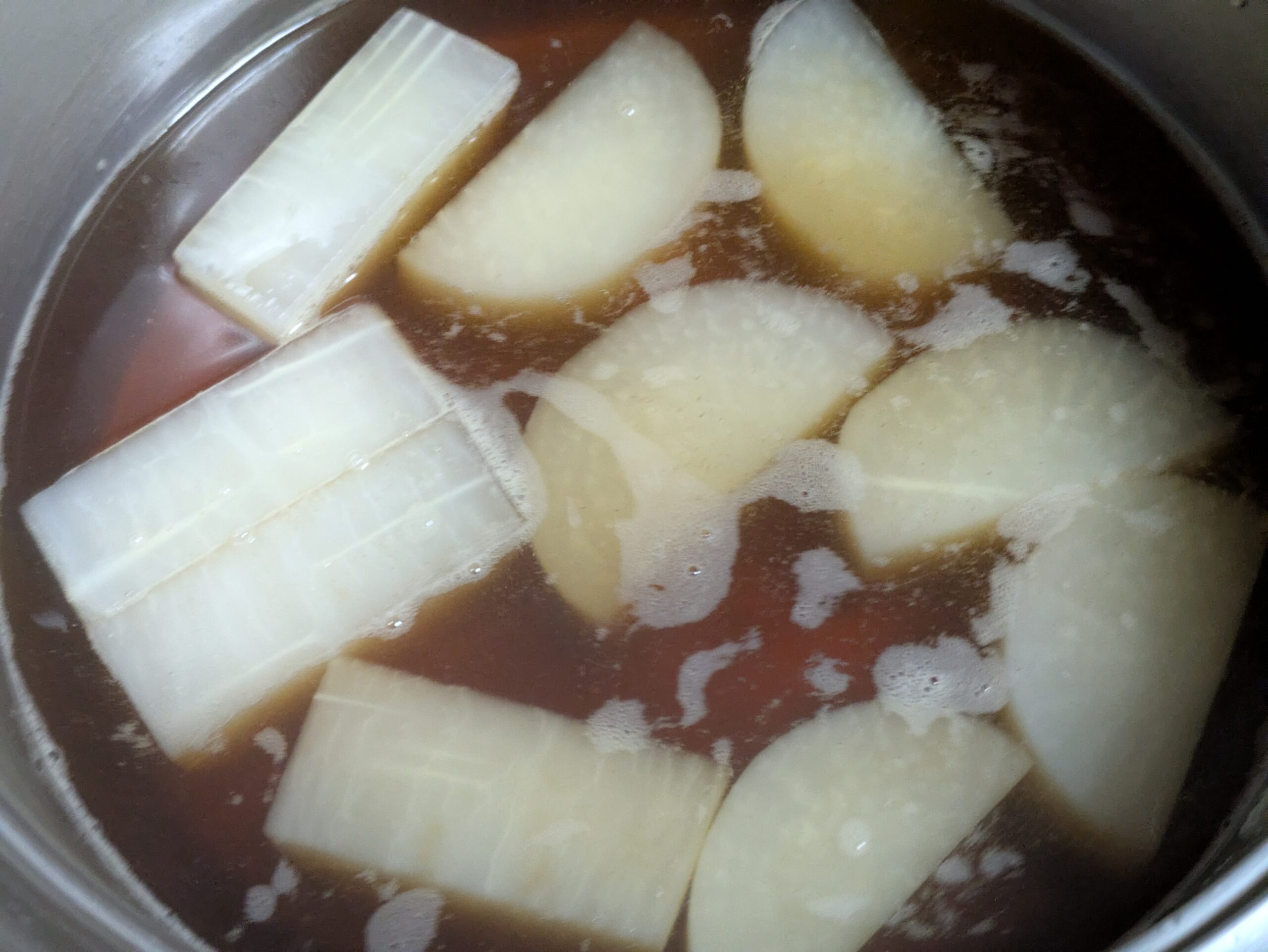 醤油やみりんを合わせた煮汁で金沢大根を煮込んでいる様子