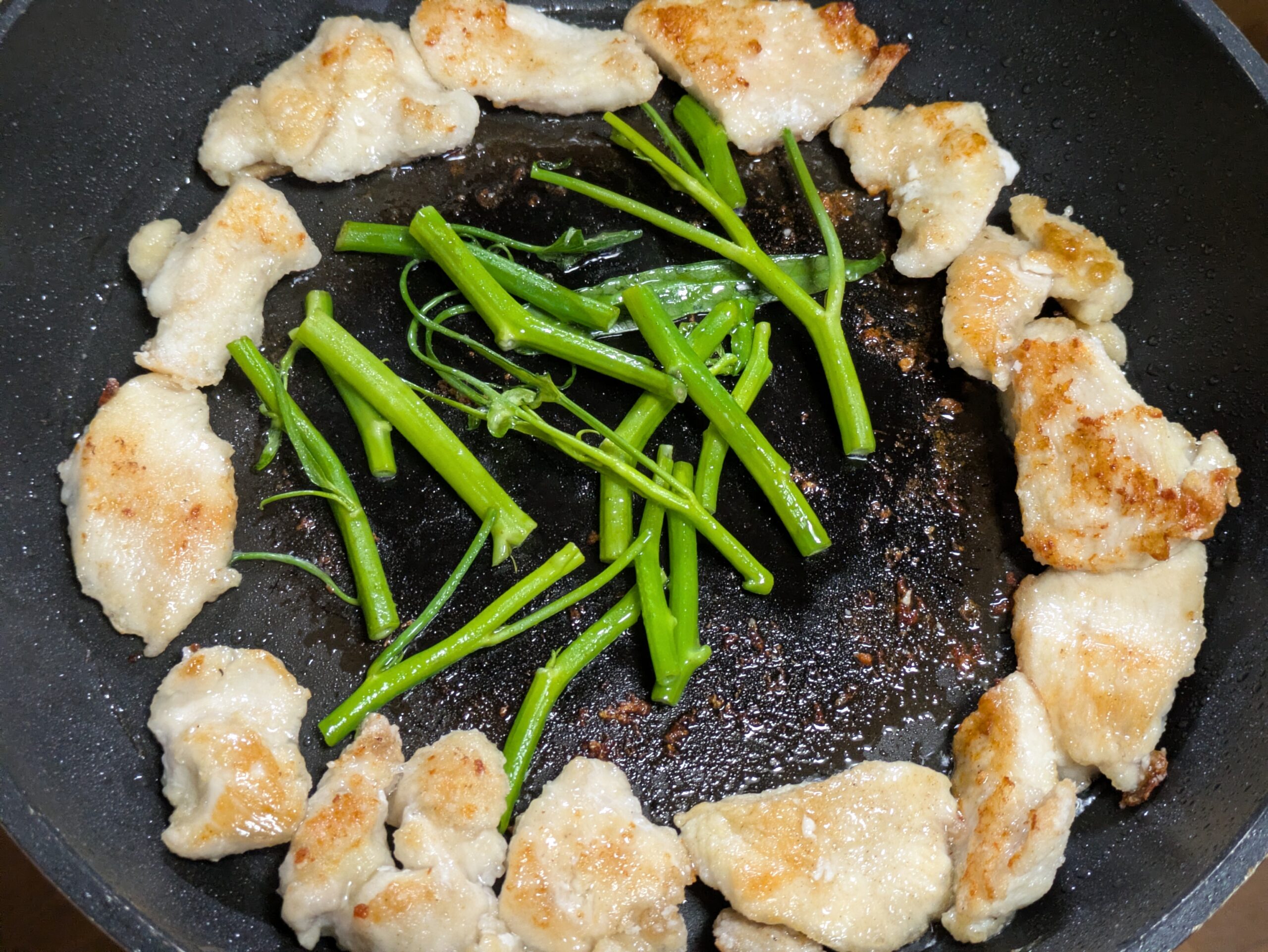 焼いた鶏むね肉と一緒にエンサイの茎を炒めているところ