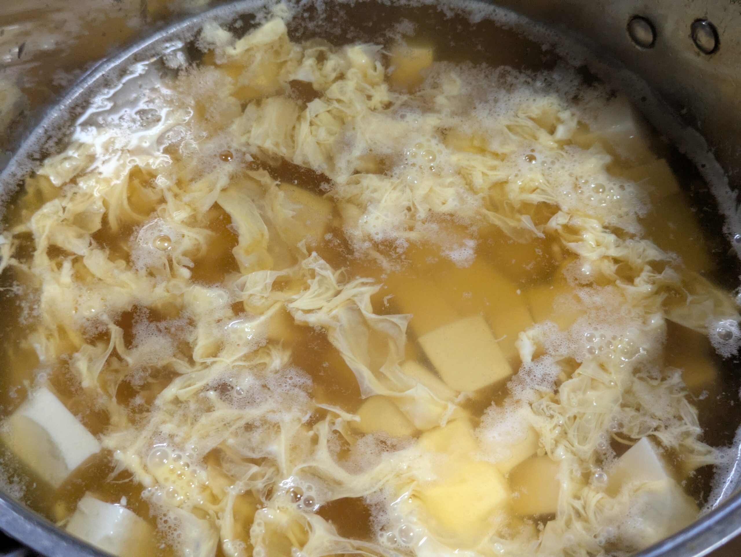 豆腐入りのスープに溶き卵を流し入れた様子