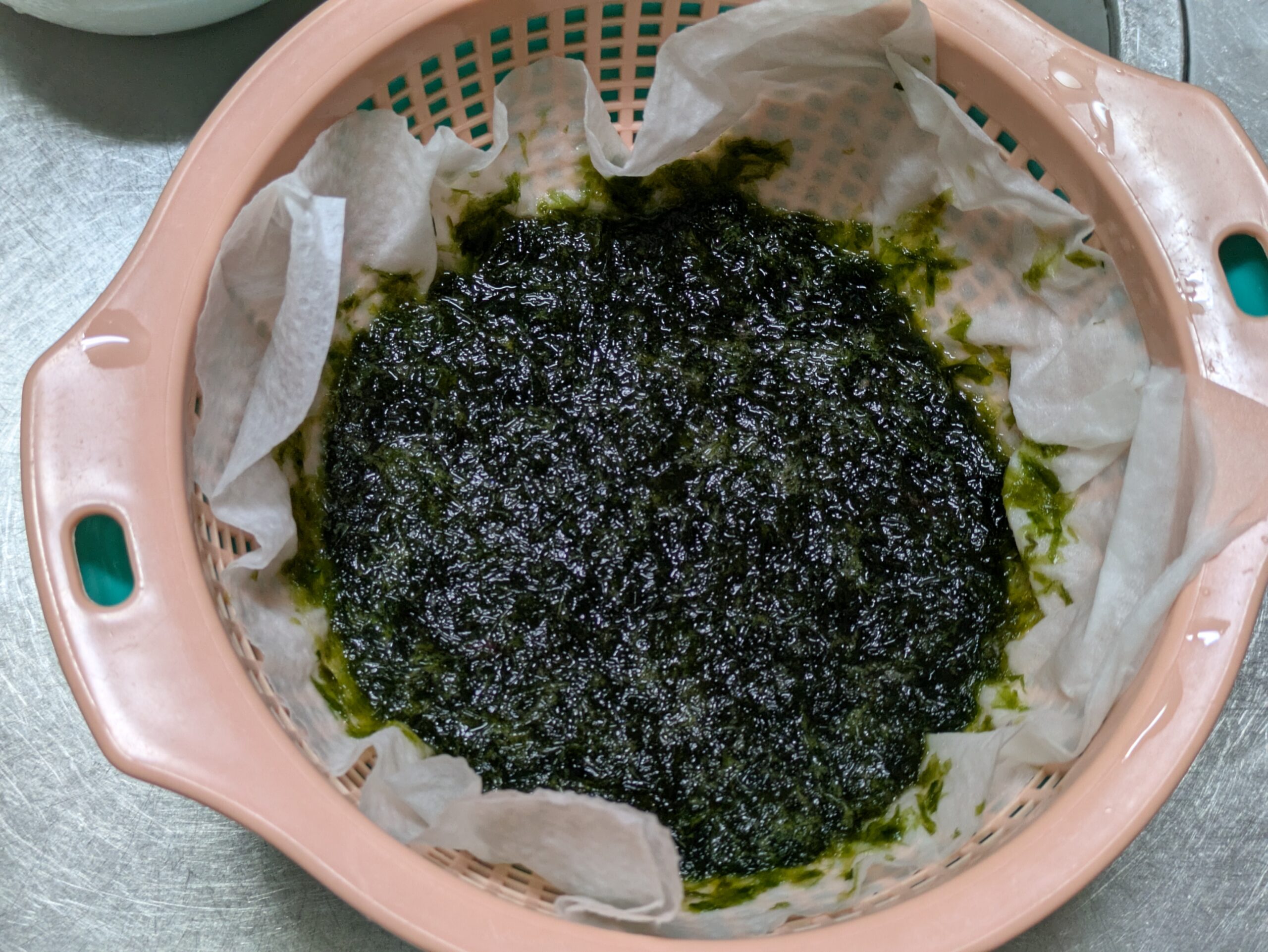 クッキングペーパーを使って洗った青さの水気を切る様子