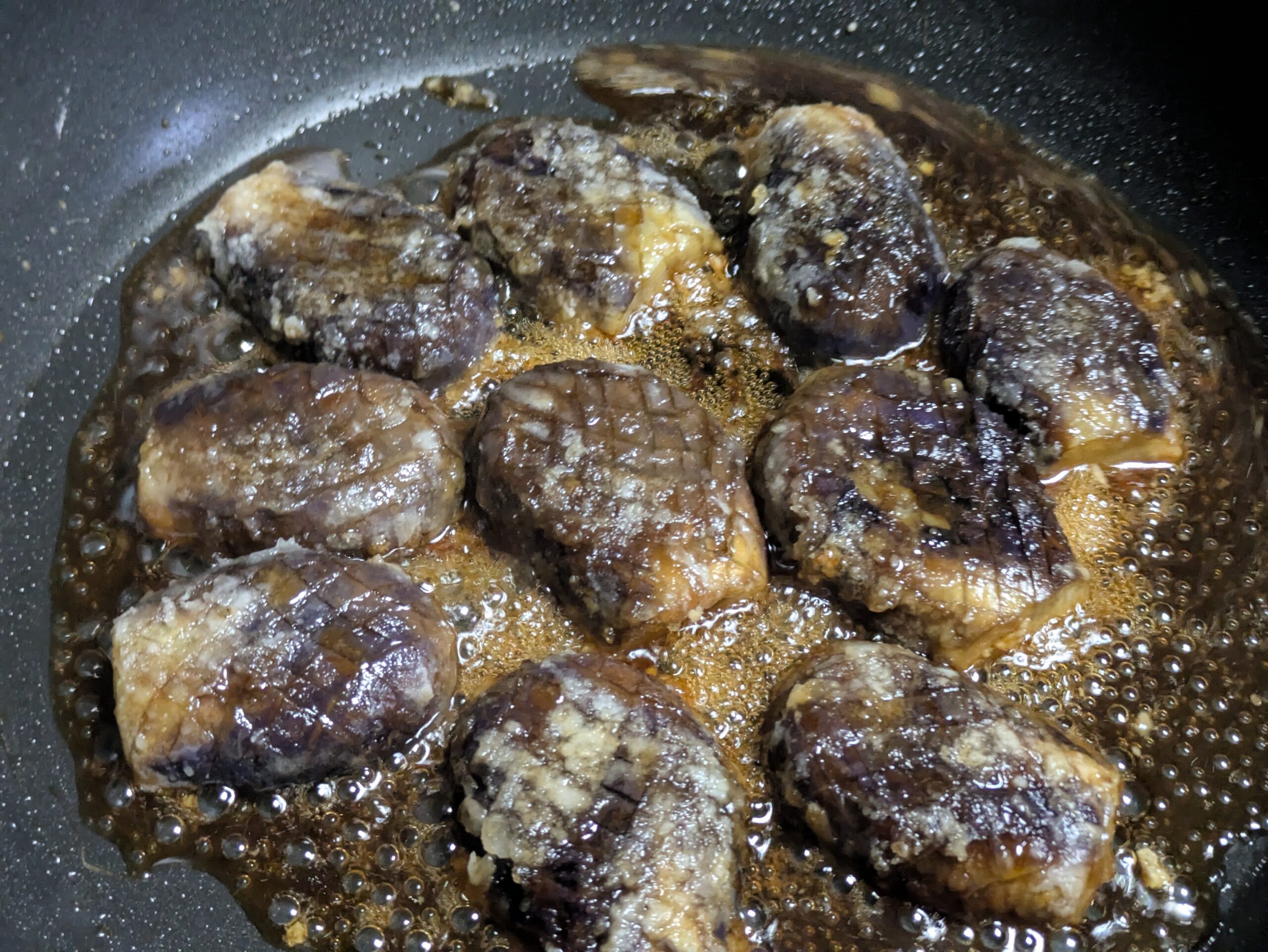 ヘタ紫なすに蒲焼きダレを絡めて煮詰めている様子