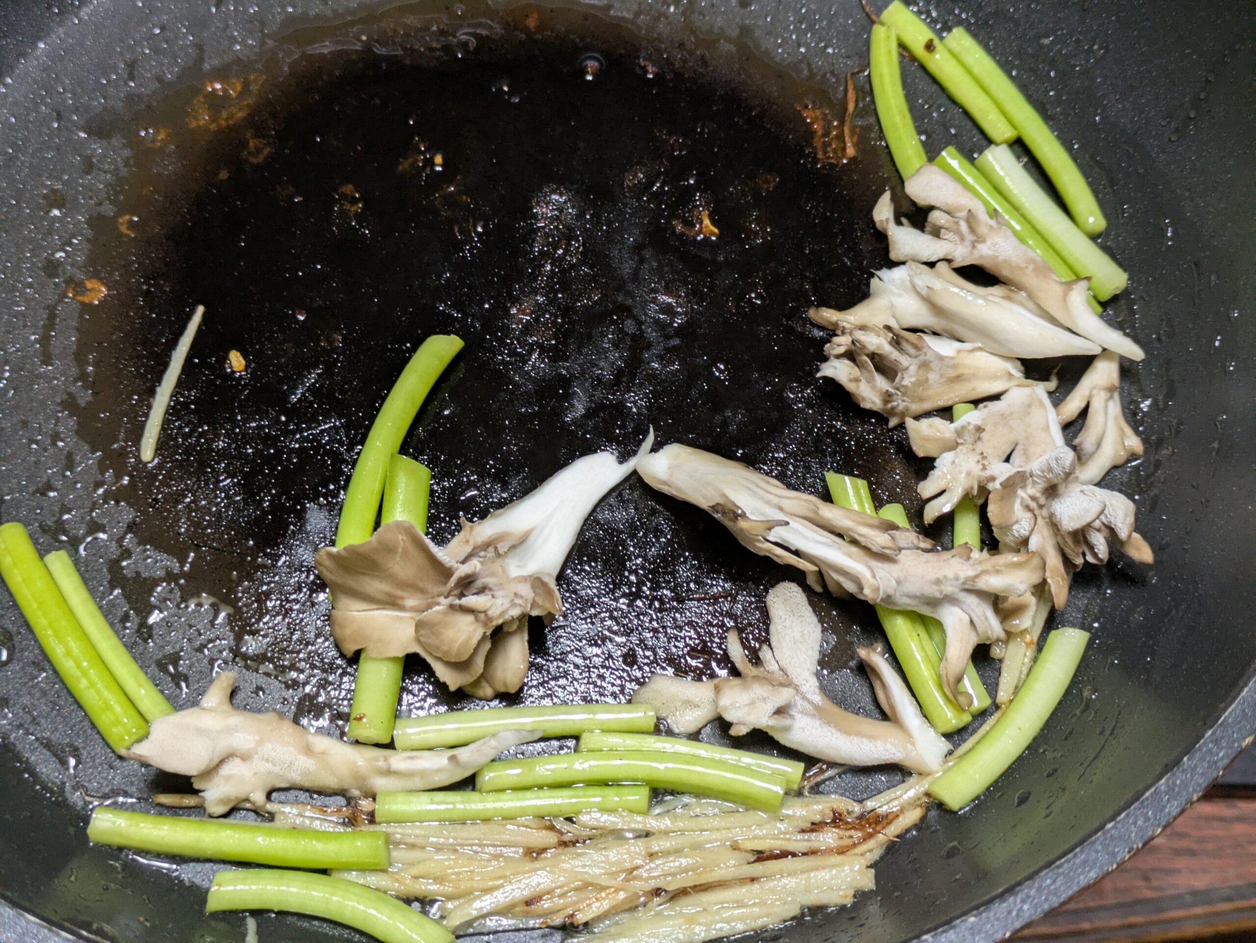 サツマイモの茎とマイタケとしょうがを炒めている様子