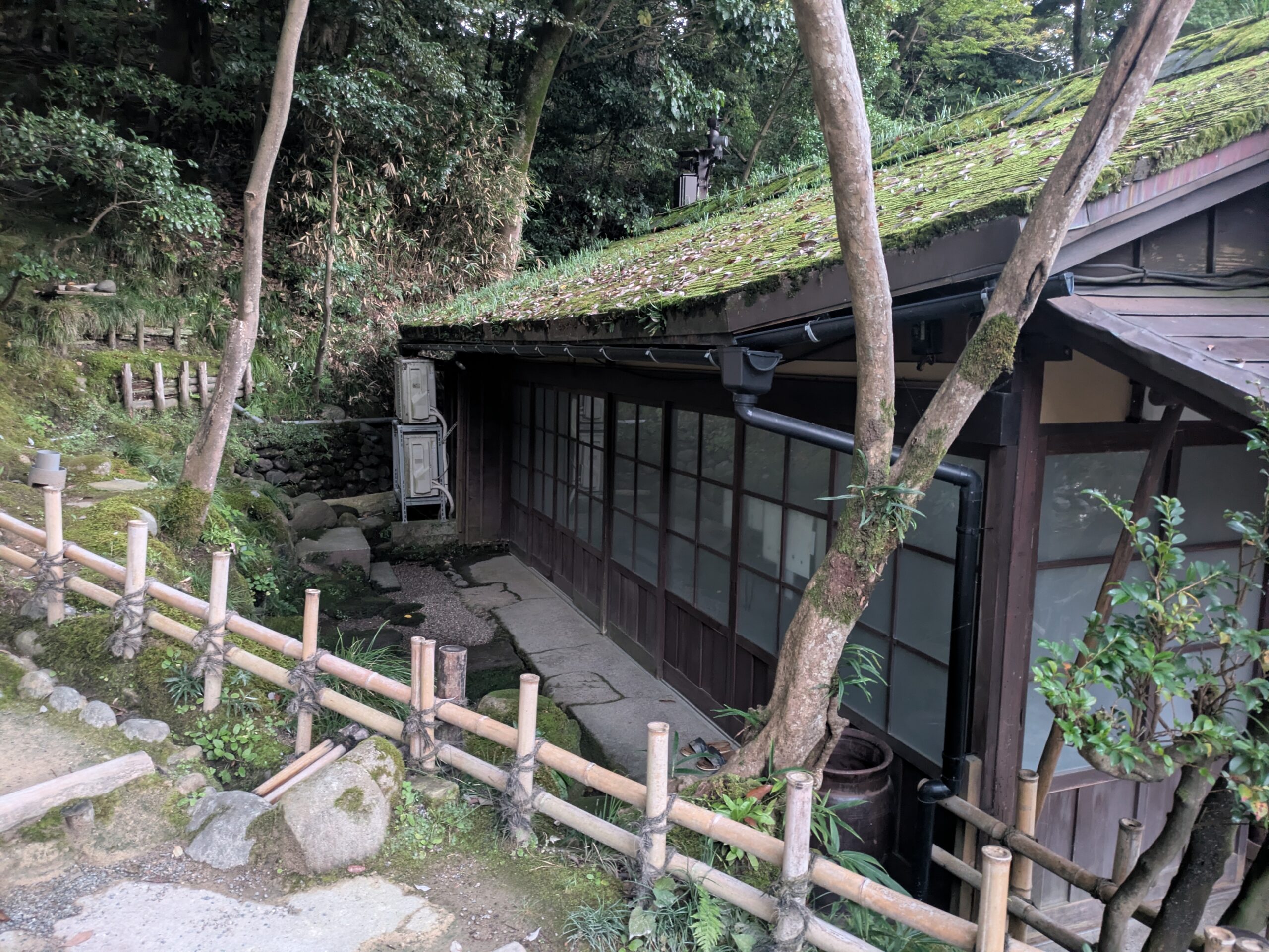 兼六園の蓮池門口近くにある苔むした屋根の建物と周囲の庭園
