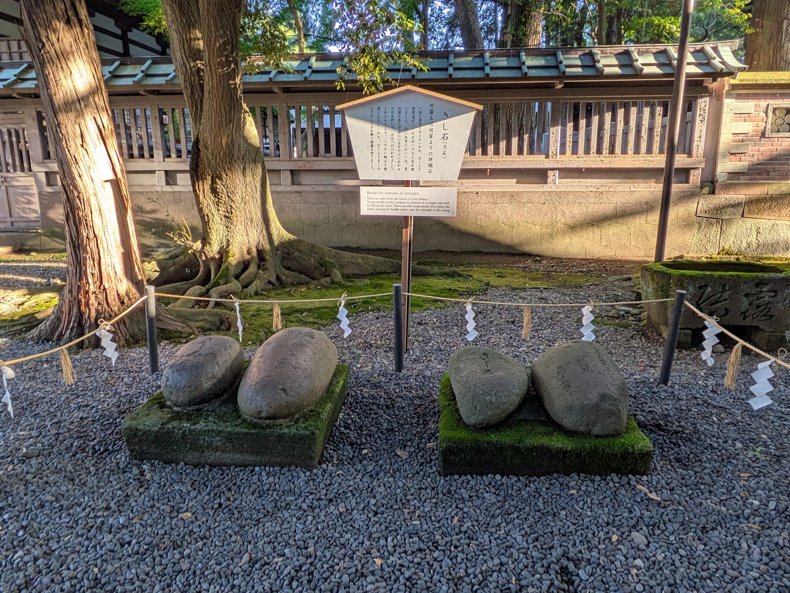 尾山神社のさし石と力比べについて説明する案内板