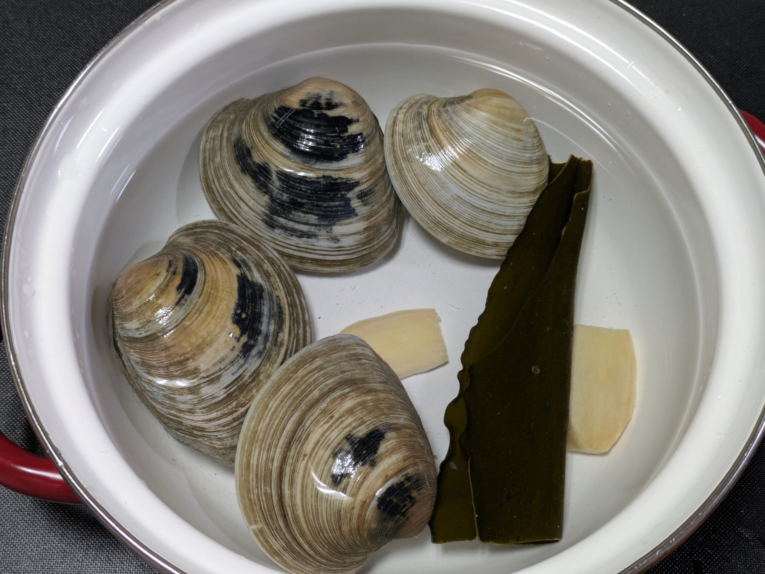 ホンビノス貝と昆布としょうがを鍋に入れて加熱する