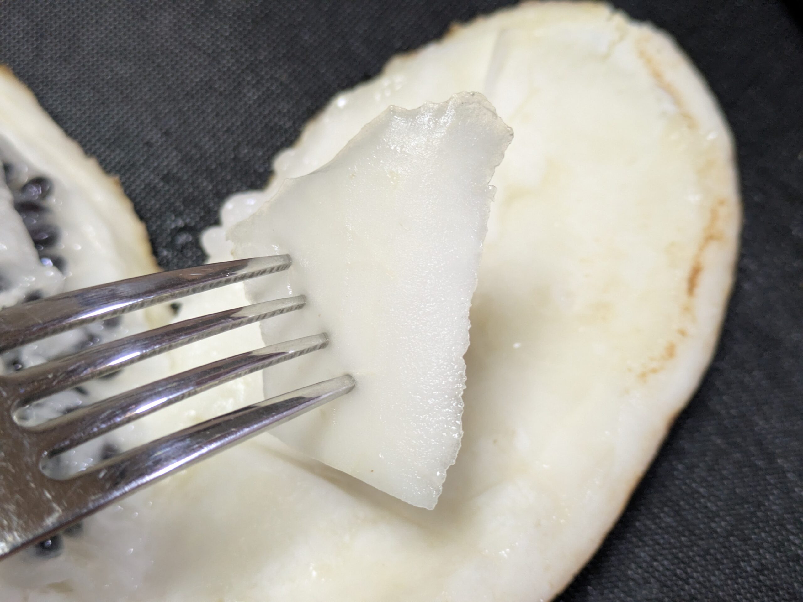 フォークで刺したアケビの白い皮の内側を試食している様子