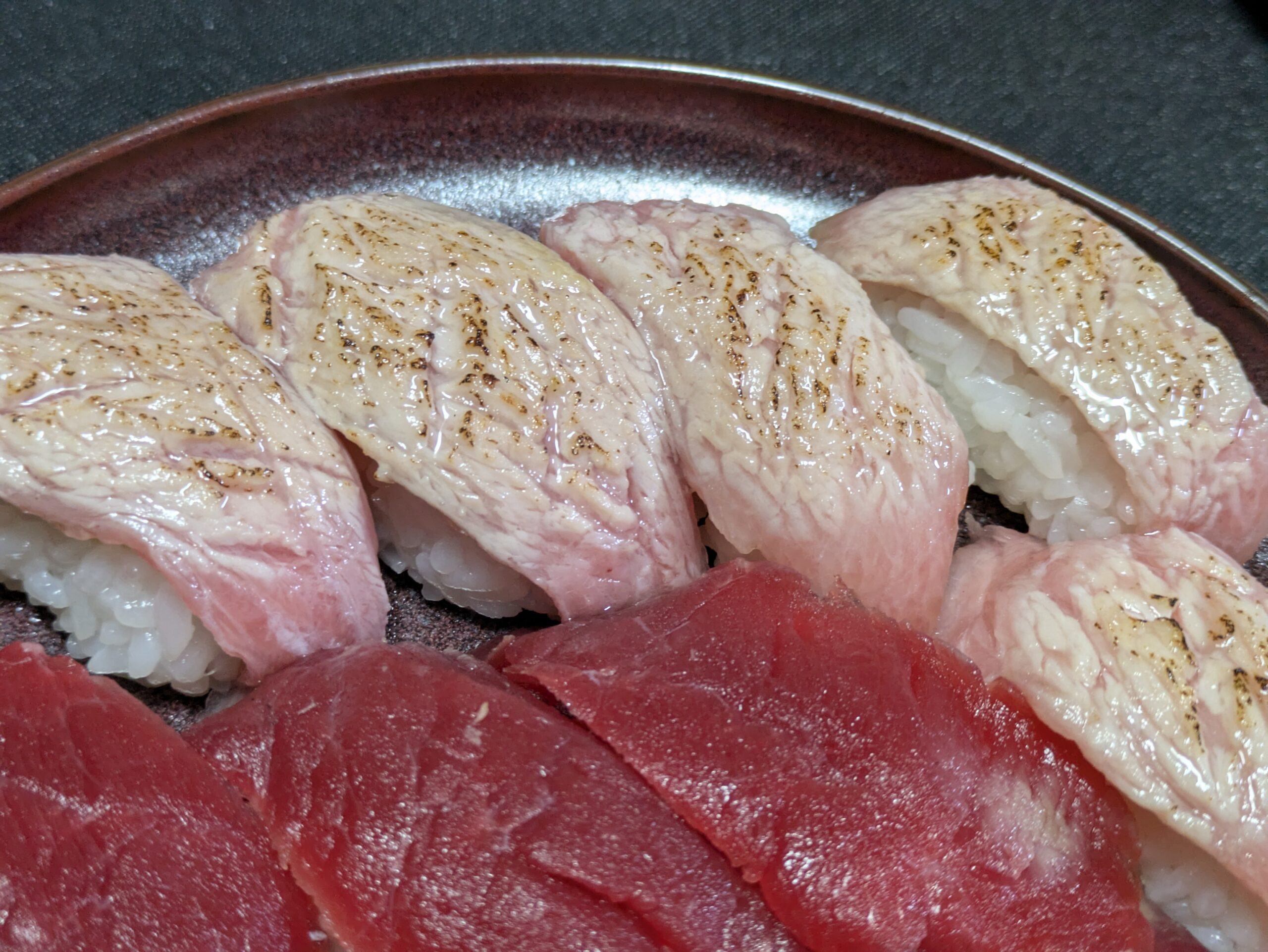バーナーで炙って表面に焼き色がついたマグロのトロ握り寿司