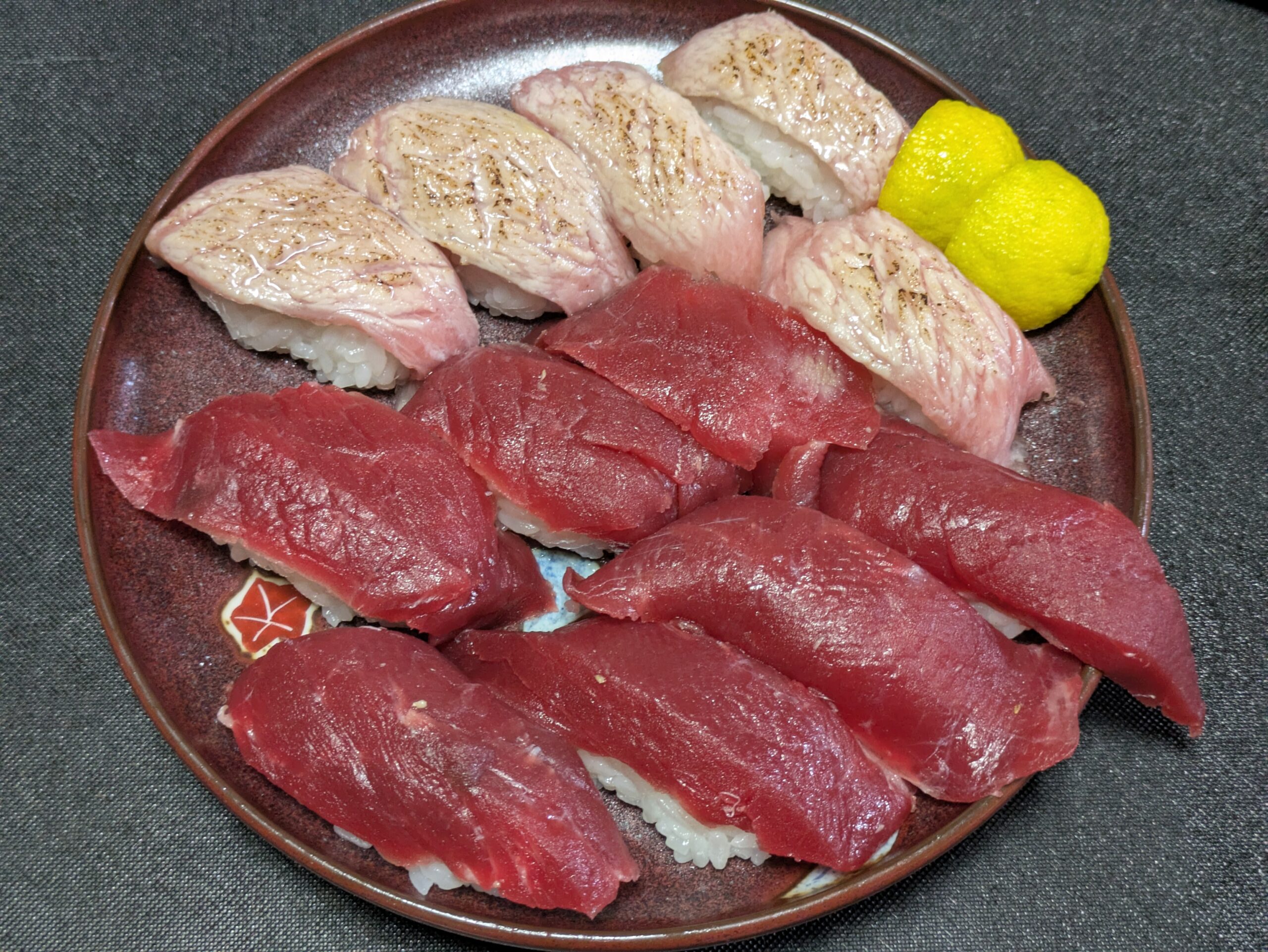 完成したマグロの赤身寿司と炙りトロ寿司に柚子を添えた盛り付け