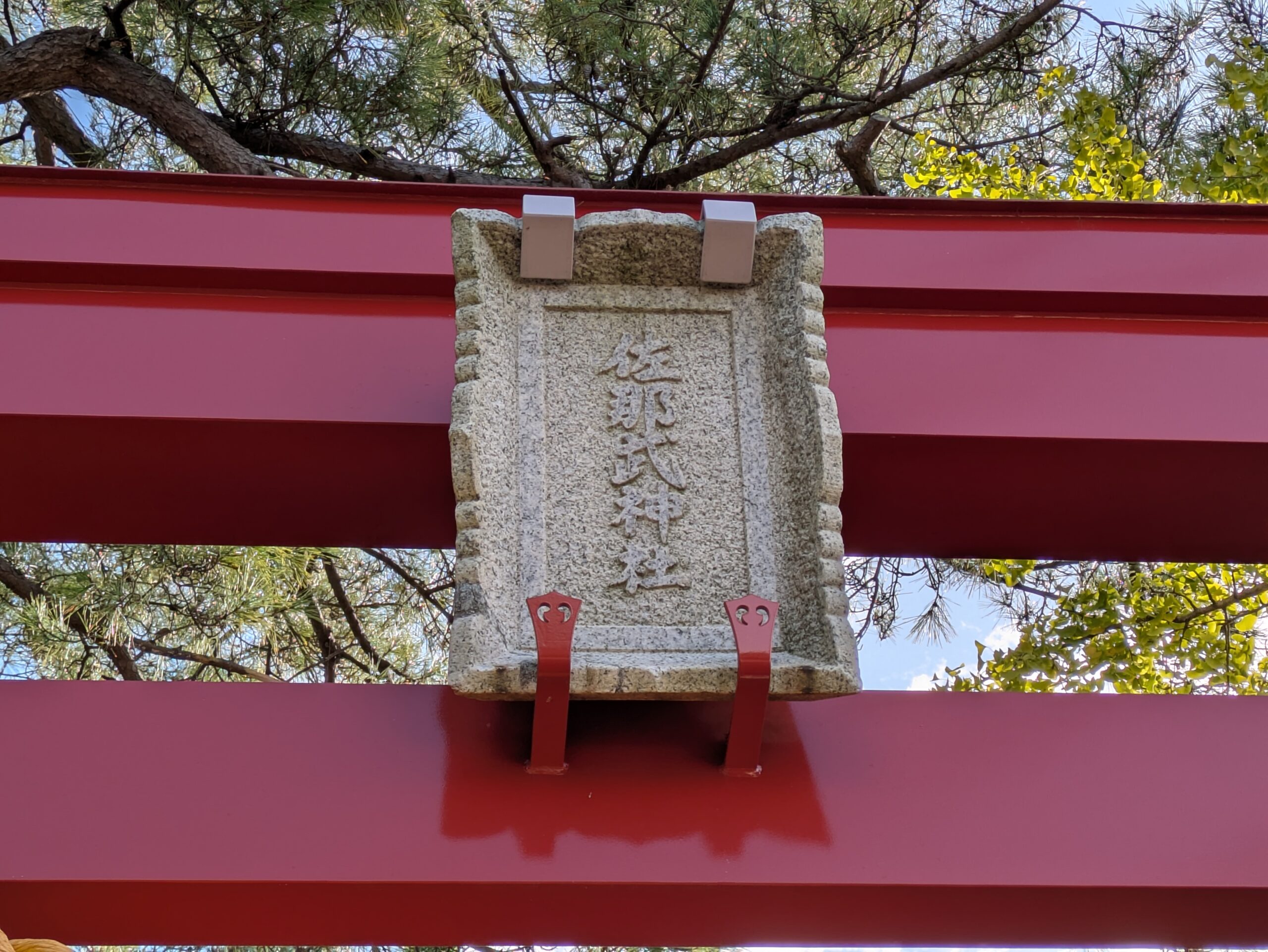 佐那武神社の朱色の鳥居に掲げられた佐那武神社と刻まれた石製の社号額