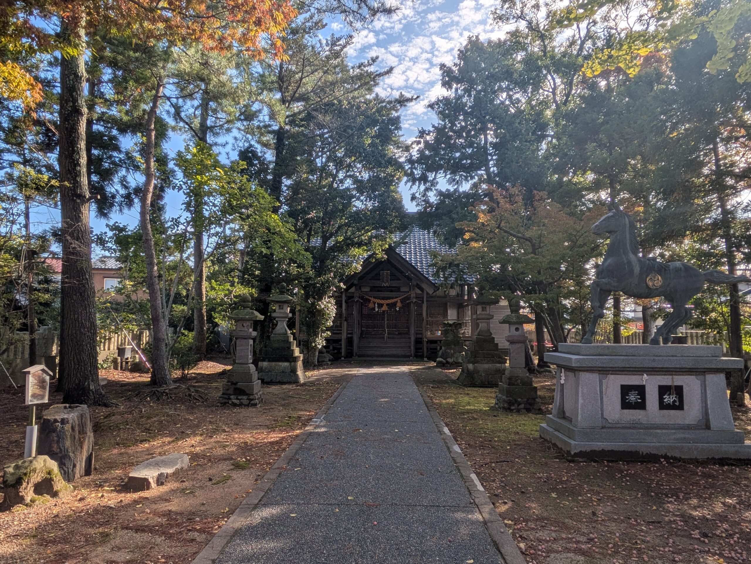 佐那武神社の参道と拝殿、石灯籠、右側に奉納された馬の像